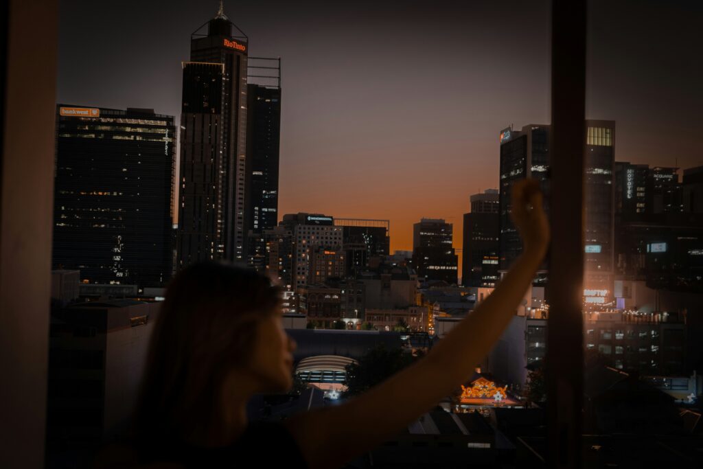 Person stands inside a modern home looking out a large, clean window at the city below, symbolizing gaining clarity on hom...