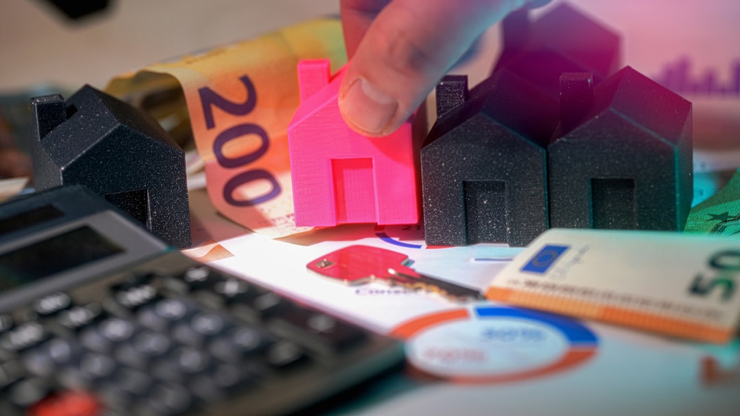 A person's hands holding a white ceramic piggy bank in front of a softly blurred background of a residential house, representing saving money on real estate commissions.