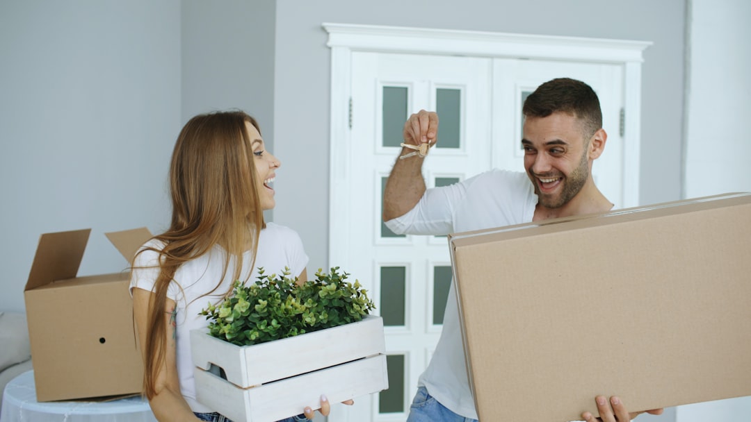 A smiling, professional couple holding up the keys to their new home, celebrating their successful property purchase.