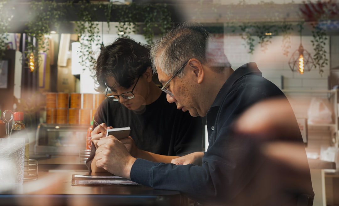 A couple sits at their kitchen table with a calculator and papers, looking concerned about their finances, illustrating the stress of calculating high real estate commissions.