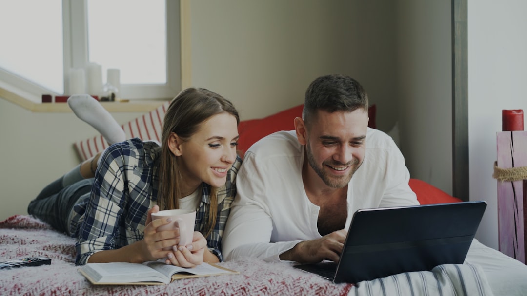 A professional couple in their modern living room using a tablet to research real estate options, representing an informed home-selling decision.