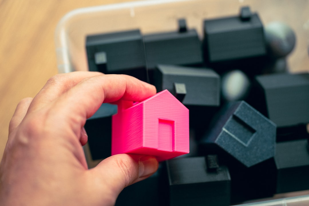 A clean, minimalist image showing a set of modern house keys next to a white, house-shaped piggy bank, symbolizing savings and equity in real estate.