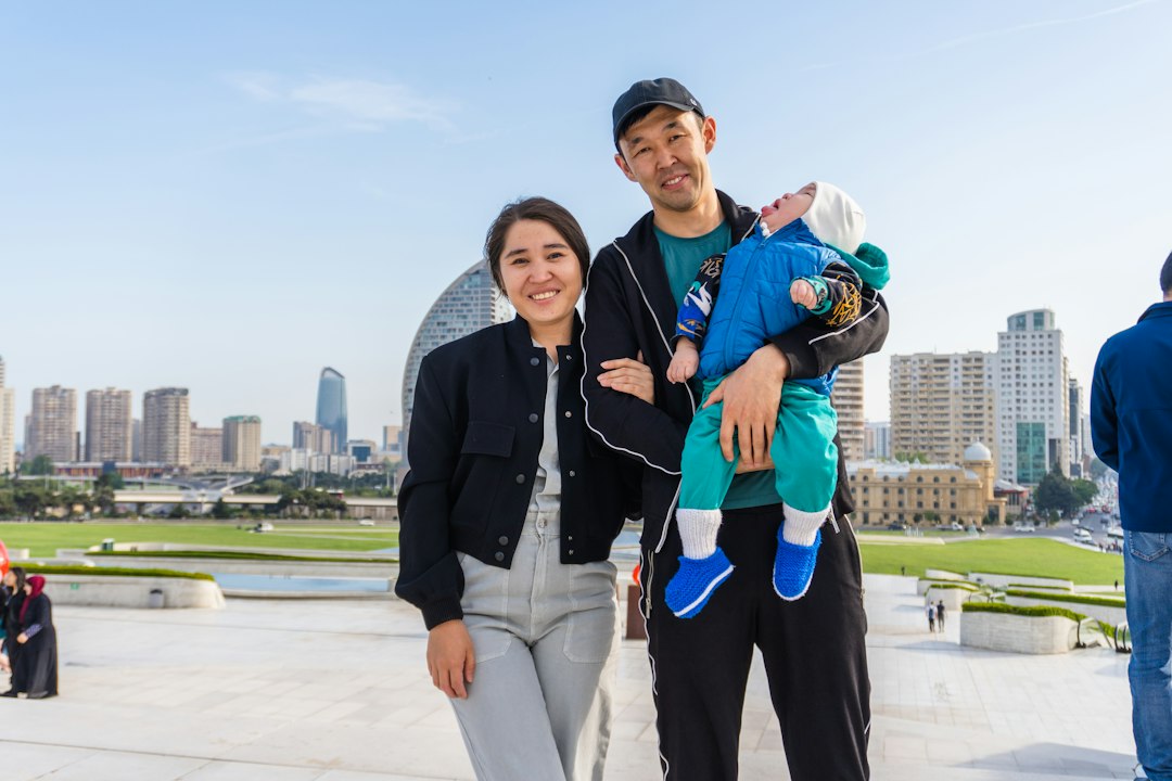 A smiling family stands proudly in front of their beautiful new Midwestern-style home on a bright, sunny day, representing a successful home sale.
