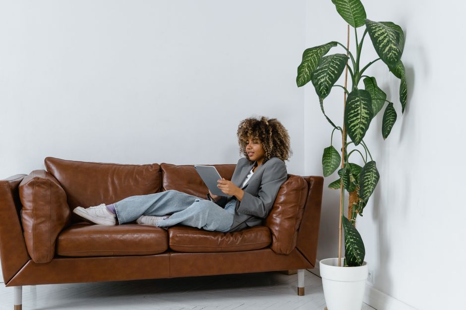 A person dressed professionally holding a digital tablet while standing inside a modern, sunlit home, illustrating the use of technology in today's real estate market.