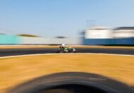 Dynamic shot of a checkered flag waving victoriously as a blurred race car speeds past the finish line, symbolizing a win.
